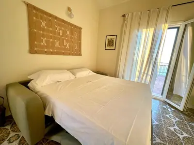 a bedroom with a white bed with a large window at Il Poggio Retreat - Cefalù in Cefalù