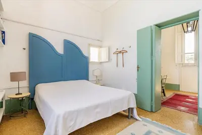 a bedroom with a large bed with a blue headboard at Tonnara Foderà di Magazzinazzi in Alcamo