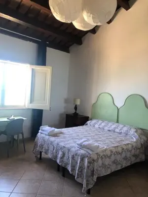 a bedroom with a bed and a table and a chandelier at Tonnara Foderà di Magazzinazzi in Alcamo