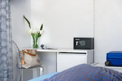 a bedroom with a desk with a tv and a vase of flowers at Araba Fenice Hotel in San Vito lo Capo