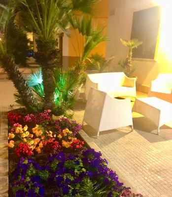 a sliding glass door with chairs and plants on a balcony at Araba Fenice Hotel in San Vito lo Capo