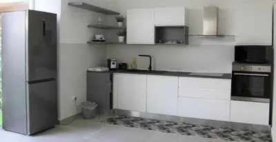 a kitchen with white cabinets and a black refrigerator at Villa Mercurio Mondello in Mondello