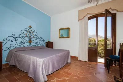 a bedroom with a bed and a large window at Baglio Buccellato in Scopello
