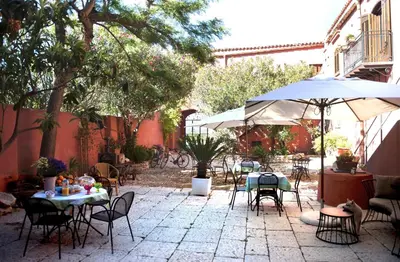 an outdoor patio with tables and chairs and an umbrella at Baglio Buccellato in Scopello
