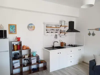 a white kitchen with a sink and a refrigerator at La casetta di rosario mondello in Palermo