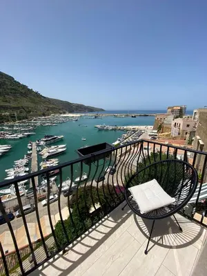 a chair sitting on a balcony overlooking a marina at La suite del Golfo in Castellammare del Golfo