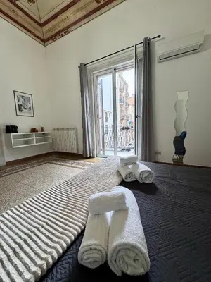 a bedroom with towels on a bed with a large window at Casetta Alice in Palermo