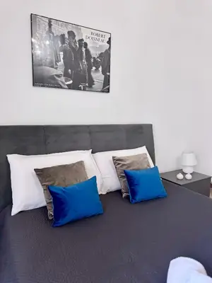 a bed with four pillows and a poster on the wall at Casetta Alice in Palermo