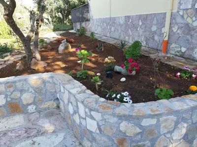 a garden with flowers and a stone wall at Villa L'orizzonte di calabianca in Castellammare del Golfo