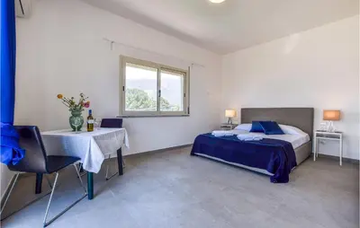 a bedroom with a bed and a table and a window at Gorgeous Home In Terrasini in Terrasini
