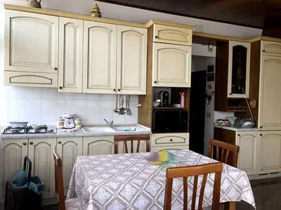 a kitchen with white cabinets and a table with a tableablish at La casa di Maria in Isola delle Femmine