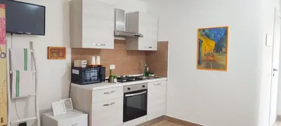 a kitchen with white cabinets and a microwave at Easy Room Holiday in Castellammare del Golfo