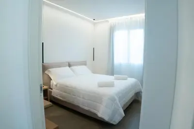 a white bedroom with a bed and a window at Hotel La Martinica in Ficarazzi