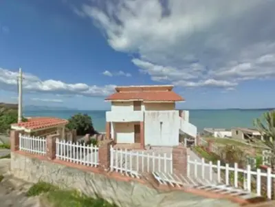 a building with a white fence next to the ocean at sizilien in Trappeto