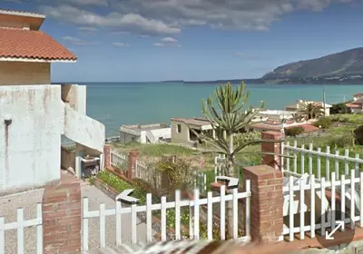 a white fence in front of a house with the ocean at sizilien in Trappeto