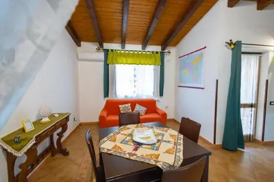 a dining room with an orange couch and a table at Tri Re e 'na Regina in Cinisi