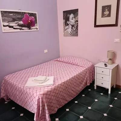 a small bedroom with a pink bed and a dresser at DayBreak B&B in Palermo