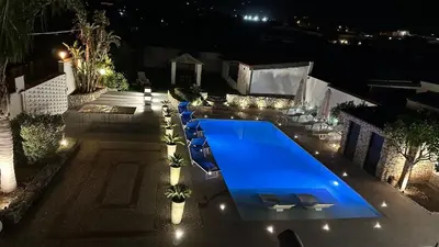 a large blue swimming pool in front of a house at night at SEALAND TERRASINI in Terrasini
