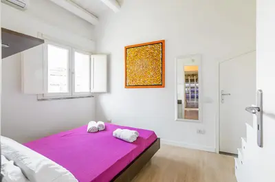 a white bedroom with two towels on a purple bed at GuestHost - Palermo Modern Apartment with Swimming Pool in Palermo