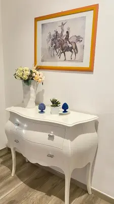 a white dresser with flowers and a picture on the wall at Rosdani Apartment in Palermo