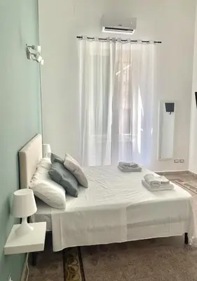 a bedroom with a white bed with a window at Stazione Armò in Palermo