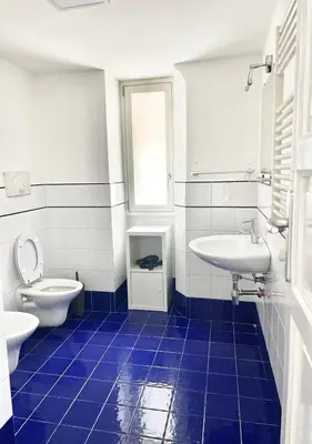 a blue tiled bathroom with a toilet and a sink at Stazione Armò in Palermo