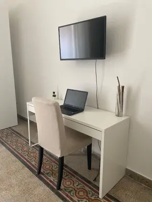 a white desk with a laptop and a tv on a wall at Stazione Armò in Palermo