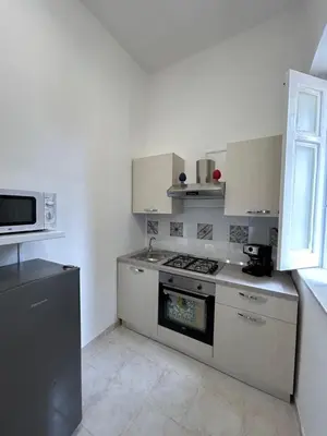 a white kitchen with a stove and a microwave at Le Trottole Apartment in Palermo