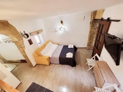 a bedroom with a bed and a couch in a room at Casetta Polì- Appartamento con terrazza - Centro Storico in Palermo