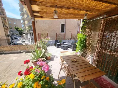 a patio with a wooden table and flowers at Casetta Polì- Appartamento con terrazza - Centro Storico in Palermo