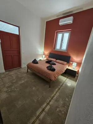 a bedroom with a bed and a red wall at Lu Màri case vacanze in Balestrate