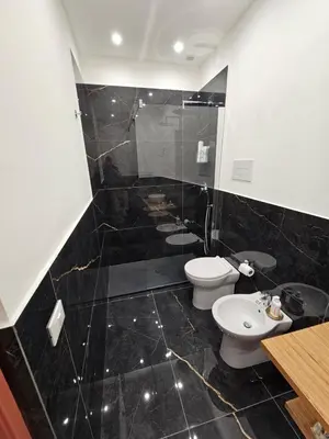 a black tiled bathroom with a toilet and a sink at Lu Màri case vacanze in Balestrate