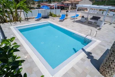 a large swimming pool with chairs and a table at holiday inn endless summer in Alcamo