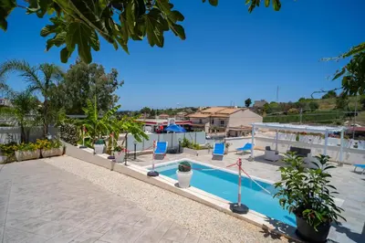a view of a swimming pool with chairs and trees at holiday inn endless summer in Alcamo