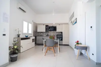 a kitchen with white cabinets and a table and chairs at holiday inn endless summer in Alcamo
