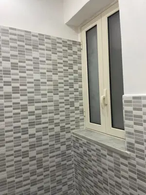 a bathroom with a tiled wall with a window at A un passo dalla cattedrale in Palermo