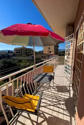 two chairs and an umbrella on a balcony at TOURIST HOUSE Le casette di Sofì in Bagheria