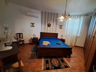 a bedroom with a bed with blue sheets and a chandelier at Villa Paola appartamento completo in Ciminna