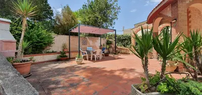 a patio with an umbrella and chairs and plants at Villa Paola appartamento completo in Ciminna