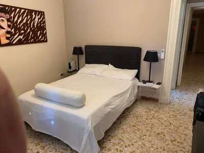 a bedroom with a white bed with a black headboard at Due Cani Apartment in Palermo