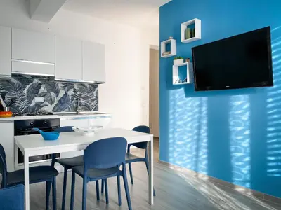 a kitchen with a white table and chairs and a tv at A Cantunera in San Vito lo Capo