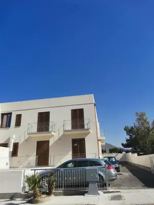 a white building with cars parked in front of it at A Cantunera in San Vito lo Capo