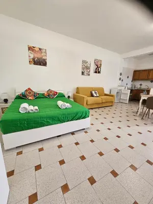 a bedroom with a green bed and a living room at casaafauka in Carini