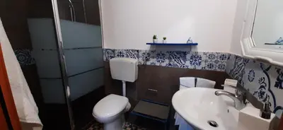 a bathroom with a white toilet and a sink at Casetta Colorata in Bagheria