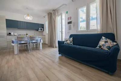 a living room with a blue couch and a kitchen at Villa Amalfi in Campofelice di Roccella