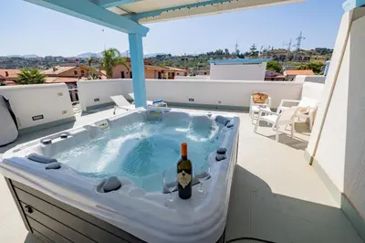 a hot tub with a bottle of wine in it on a balcony at Villa Amalfi in Campofelice di Roccella