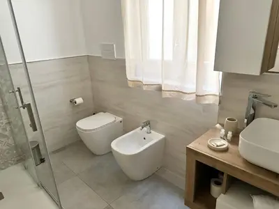 a white bathroom with a toilet and a sink at HOLIDAY HOUSE ORLANDO in Palermo