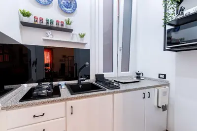 a kitchen with white cabinets and a sink at Stabile 16 Apartment in Palermo