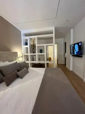 a bedroom with a large white bed and a flat screen tv at La Casetta delle Strelizie in Palermo