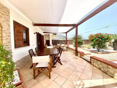 an outdoor patio with a wooden table and chairs at Casa Perla Marina sul mare in Castellammare del Golfo